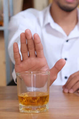 Мужчина отказывается жестом от стакана с алкоголем